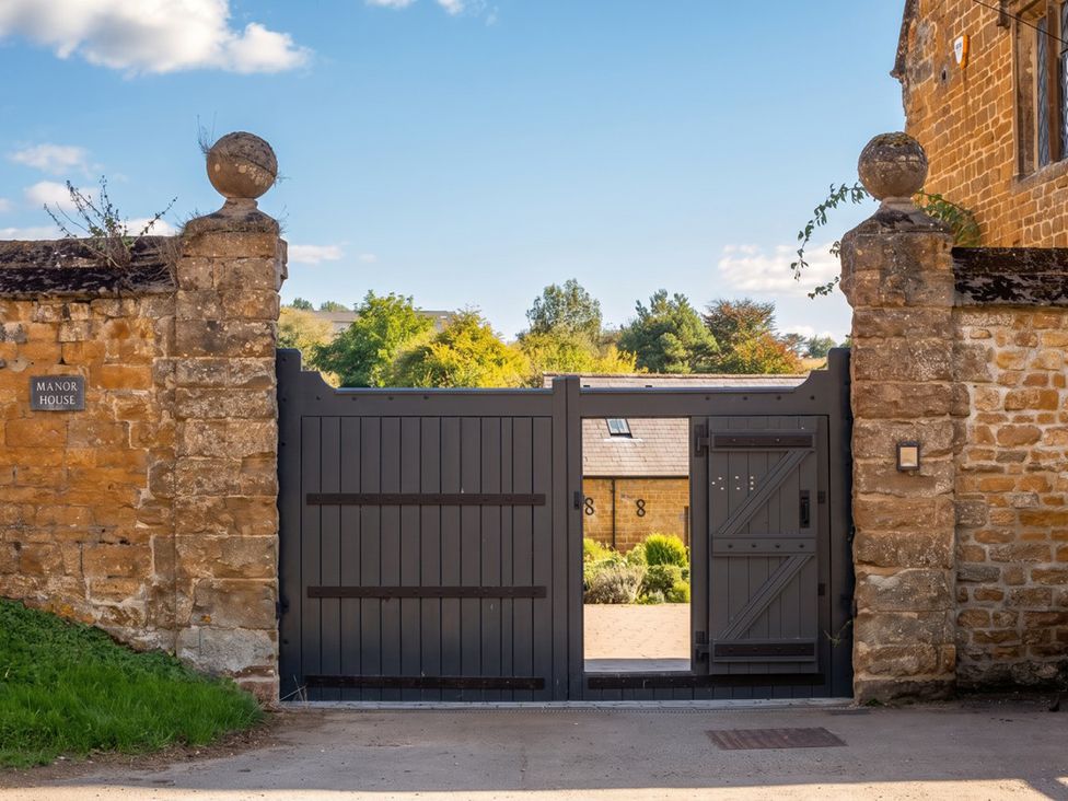 A gate with a stone wall and a sign at Manor House