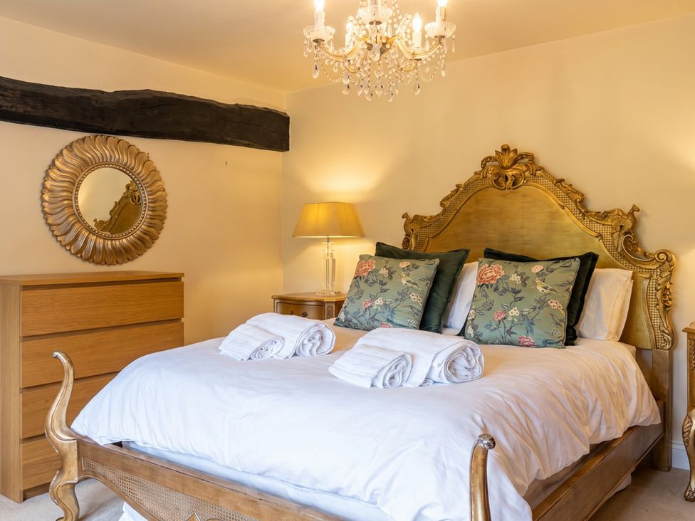 A bedroom with a bed, dresser, and chandelier at The Old Barn in Manchester