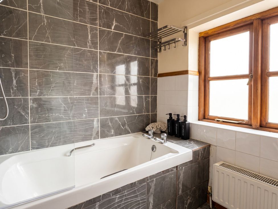 A bathroom with a bathtub and window at The Old Barn in Manchester
