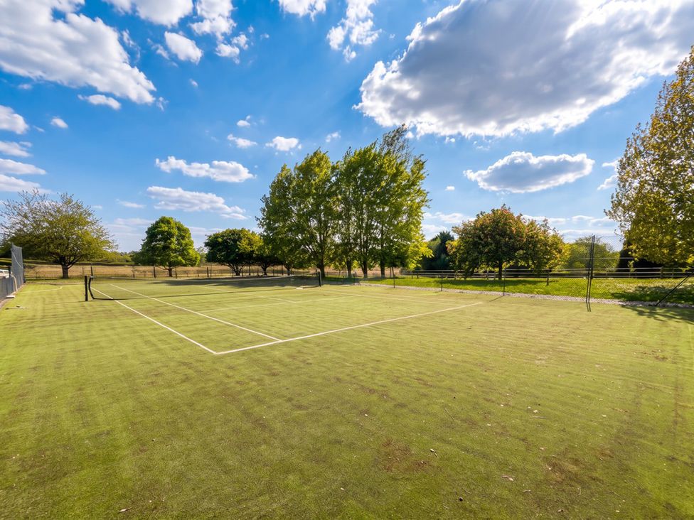 A tennis court with trees and a fence in a field