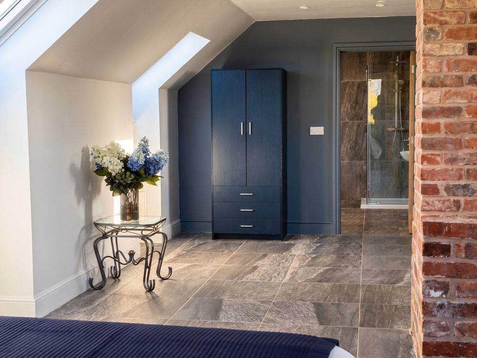 A bedroom with a wardrobe and a glass table with flowers at The Old Barn in Manchester