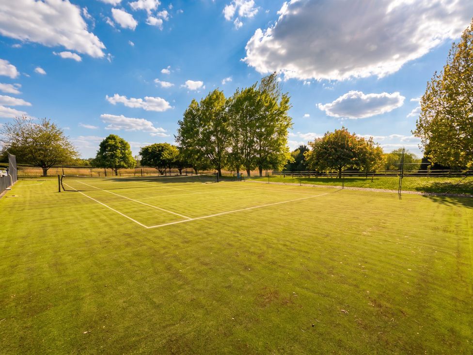 A tennis court with trees in the background and a blue sky