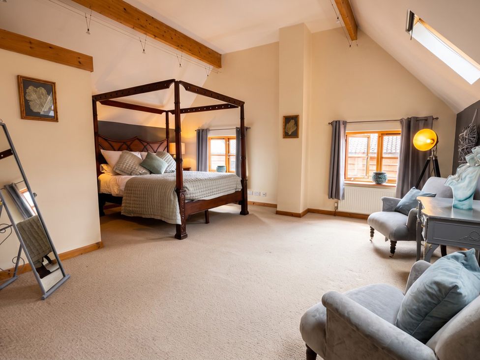 A bedroom with a four poster bed and seating area at The Old Barn in Manchester