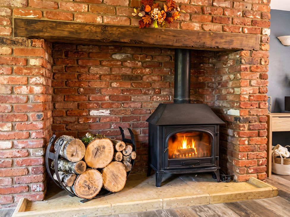 A fireplace with logs and a wood stove in a living room
