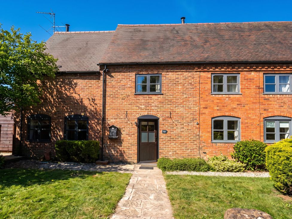 A brick house with a front door and windows at Star Cottages in a garden