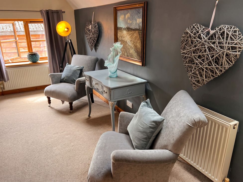 A living room with chairs, a table, and a vase at a property