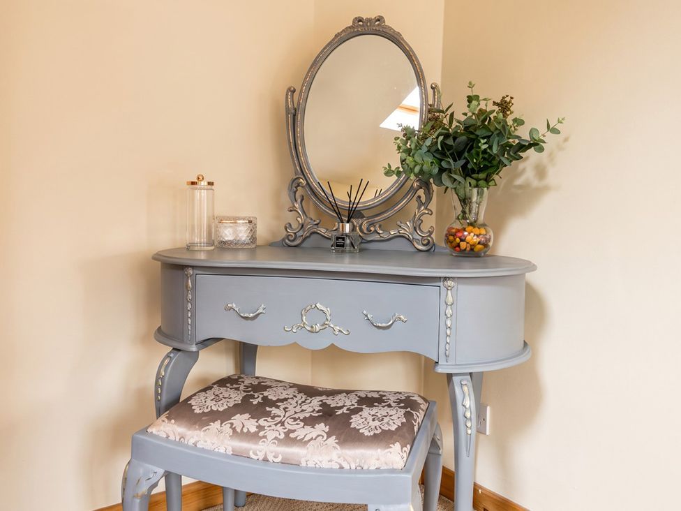 A dressing area with a grey vanity table and mirror at 