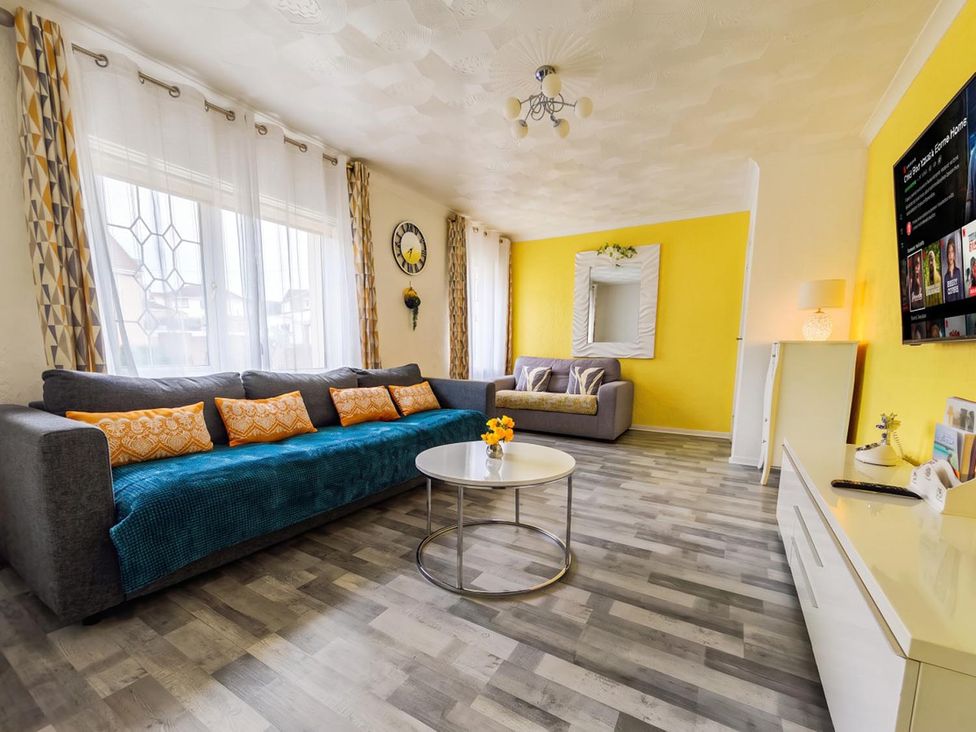 A living room with a grey sofa and yellow walls at The Old Barn in Manchester