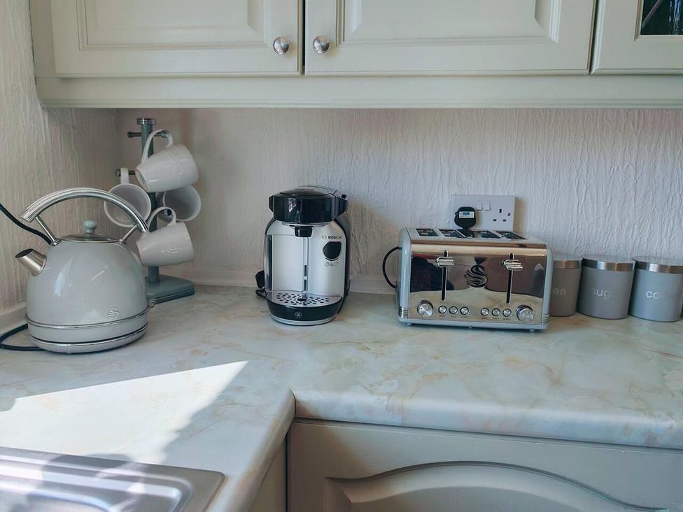 A kitchen countertop with a kettle, coffee machine, toaster, and canisters at a property