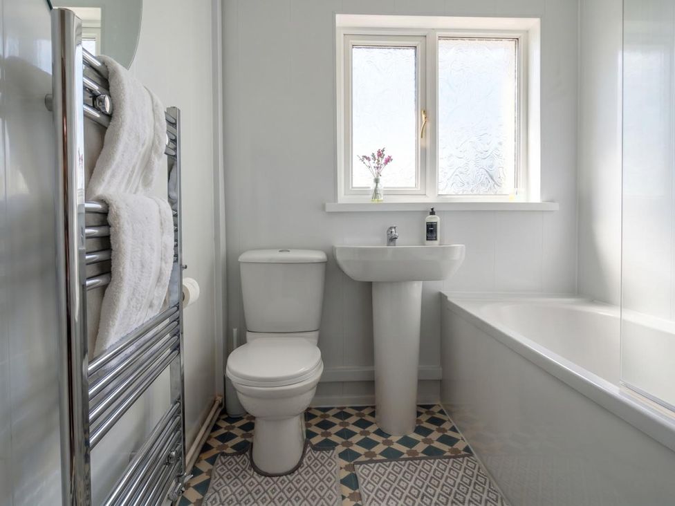 A bathroom with a toilet, sink, bathtub, and towel rack at The Old Barn in Manchester