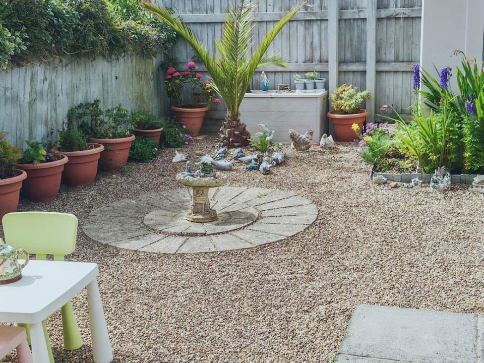 A garden with a birdbath and flower pots at a residential property