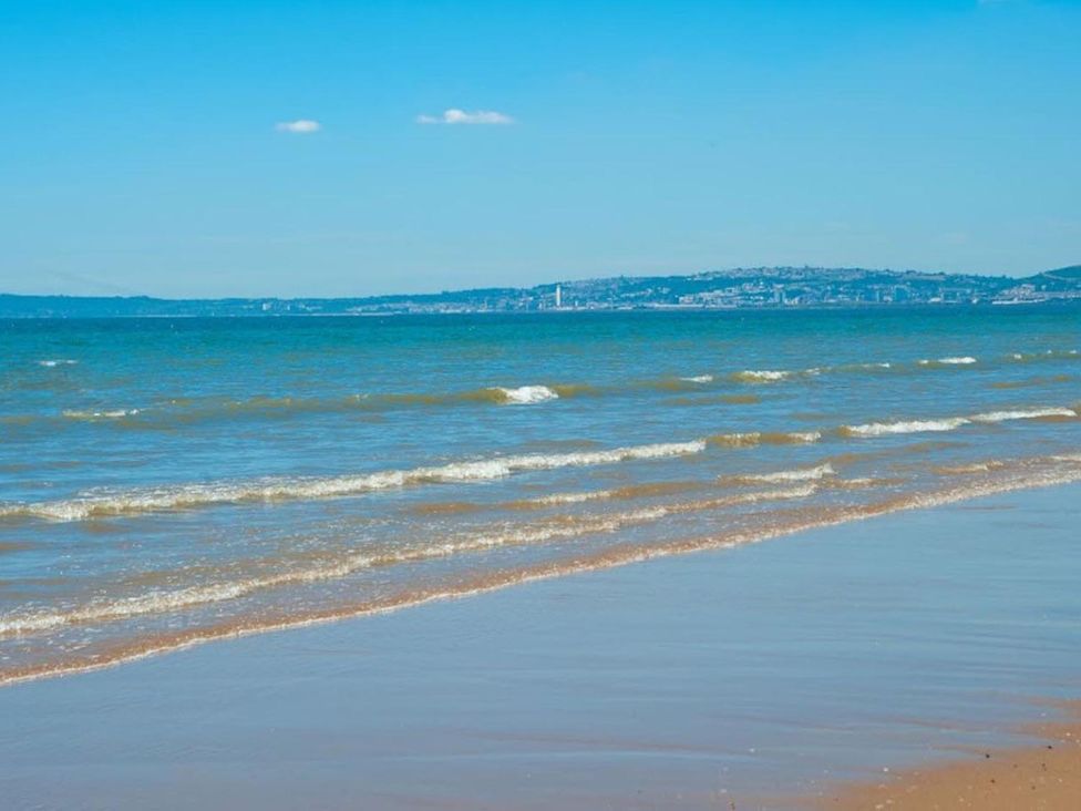 A beach with waves and clear sky at the shore