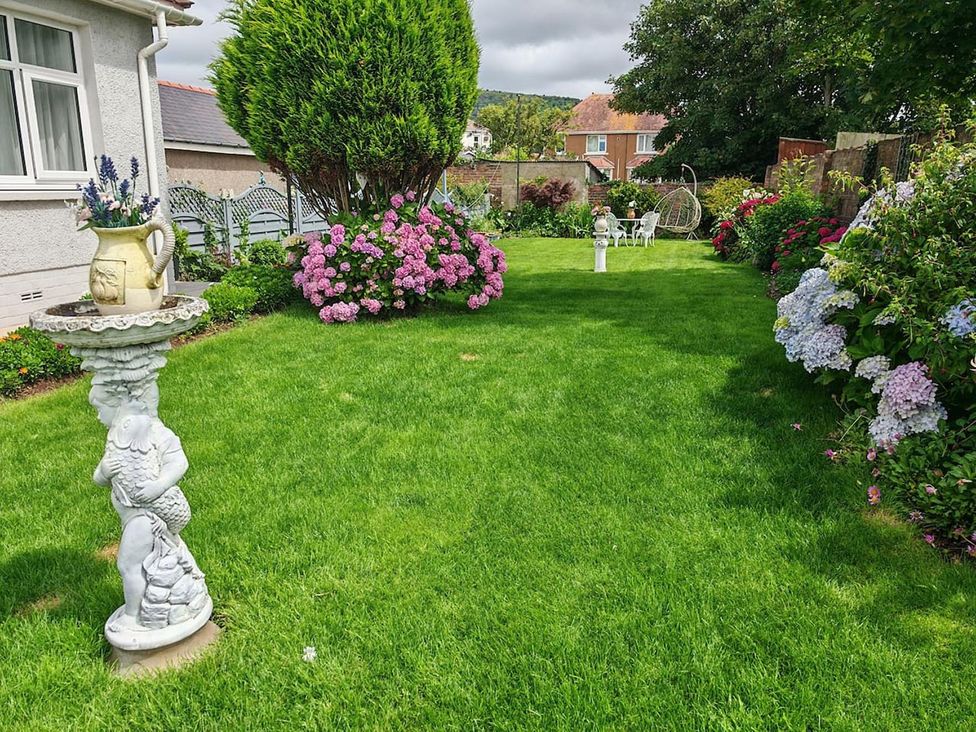A garden with flowers and a stone statue at The Old Barn in Manchester