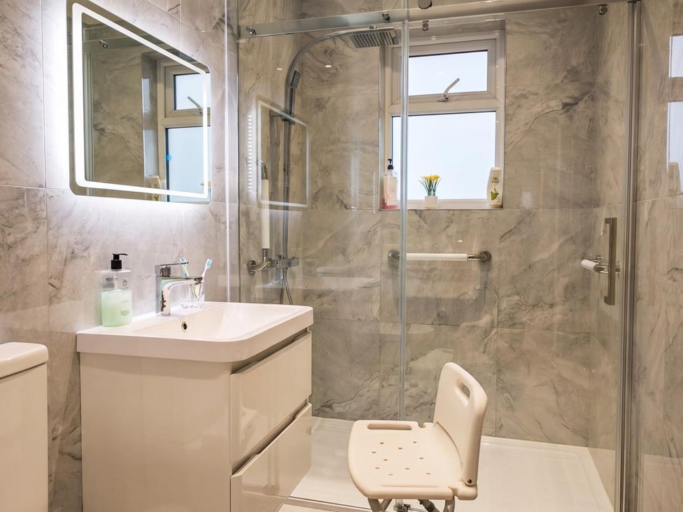 A bathroom with a shower, sink, and toilet featuring a shower chair at '' in ''