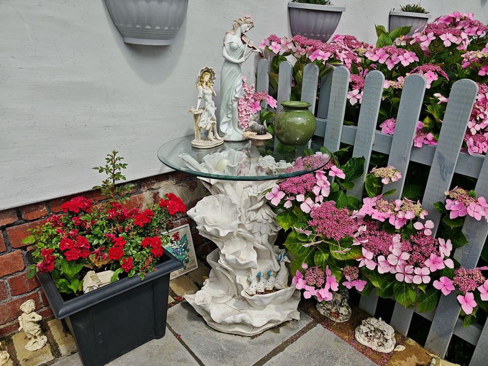 A garden with a glass table and flower pot at '' in ''
