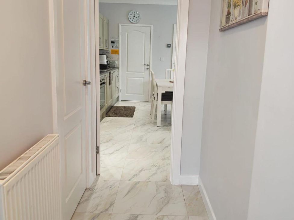 A hallway leading to a kitchen with a table and chairs at a residential property