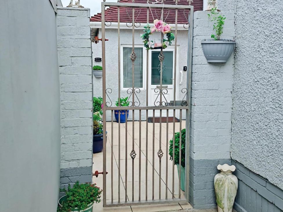 A garden gate with plants and a house in the background at the property