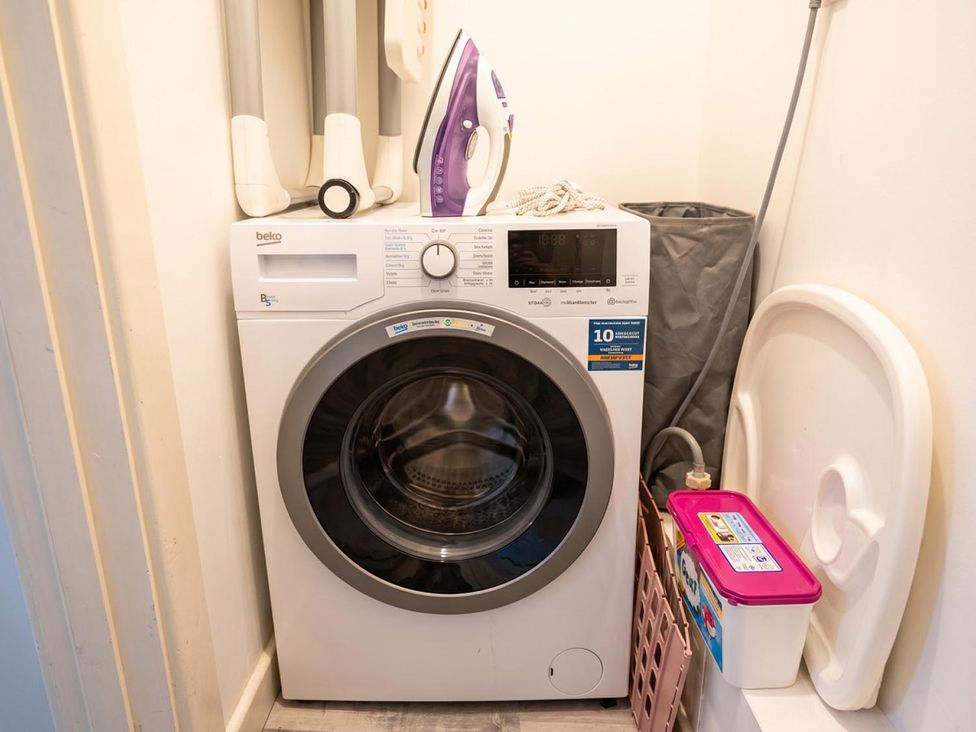 A washing machine with an iron and laundry basket in a laundry room at 
