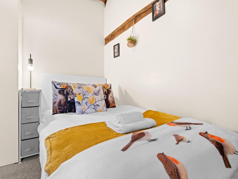 A bedroom with a bed, nightstand, and wall art at 