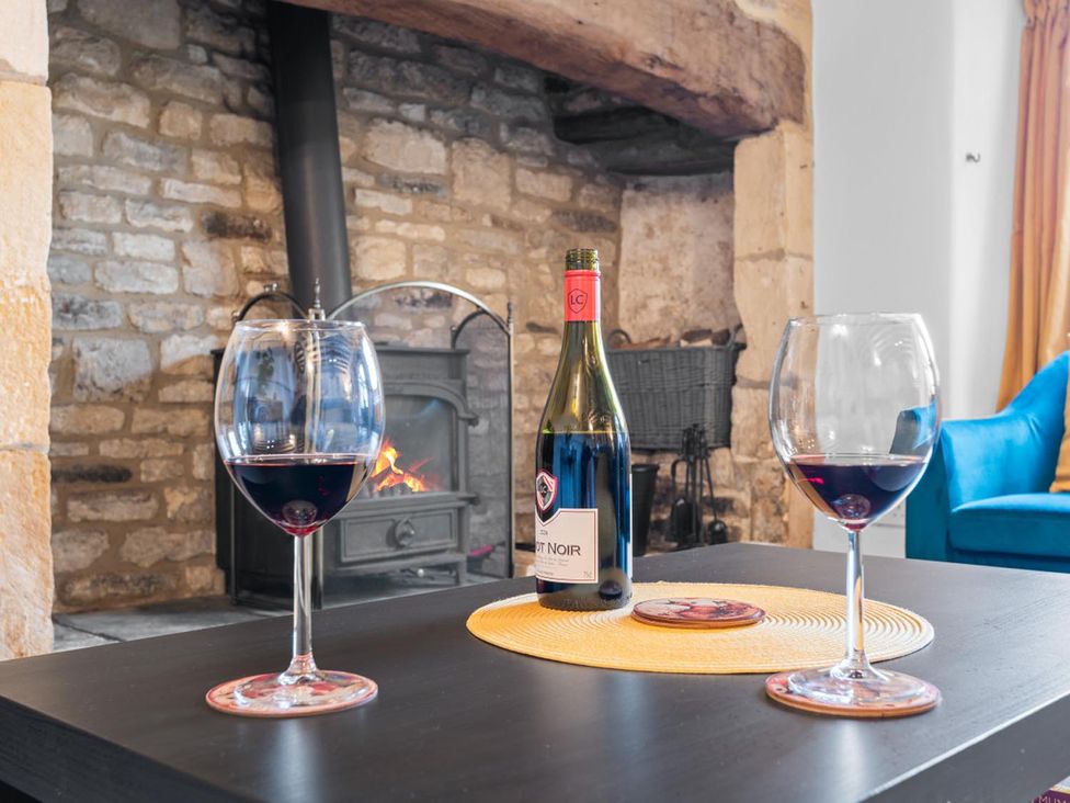A living room with wine glasses and a bottle on a coffee table by a fireplace at 