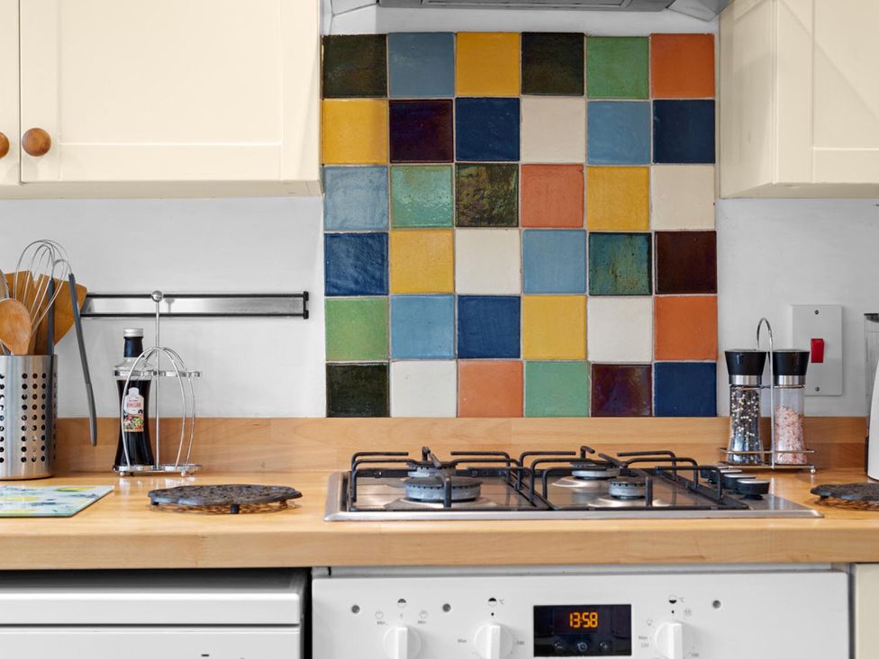 A kitchen countertop with gas stove and colorful tiles at 