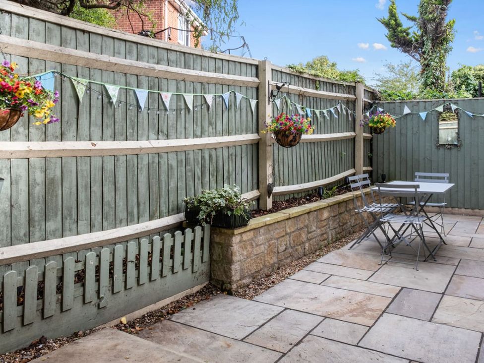 A garden with a patio, table, and hanging baskets at the property in 