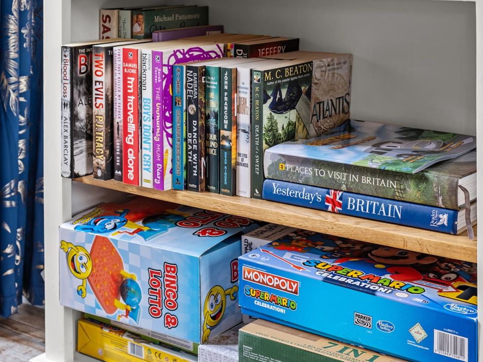 A shelf with books and board games in a living room
