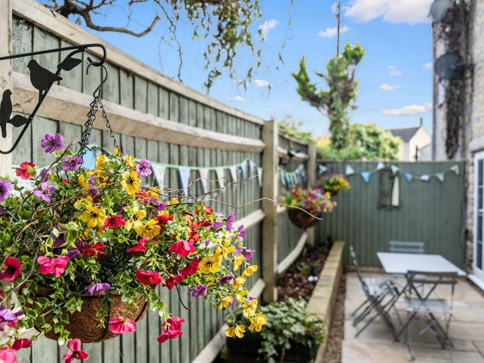 A garden with flower baskets and a table with chairs