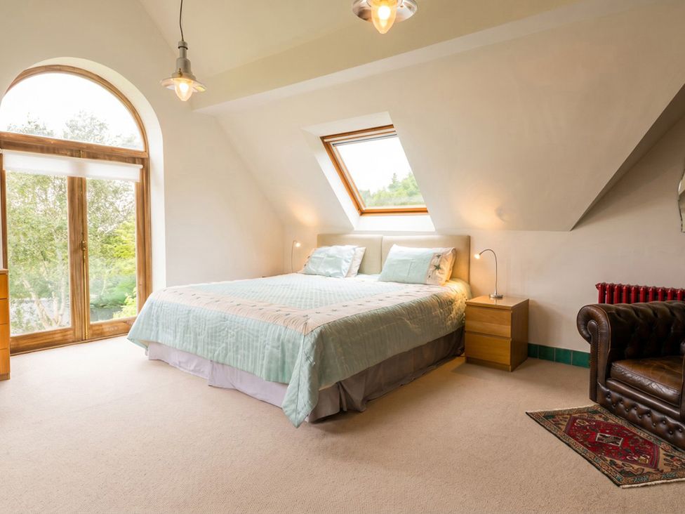 A bedroom with a bed, nightstand, and windows at the property in unspecified location