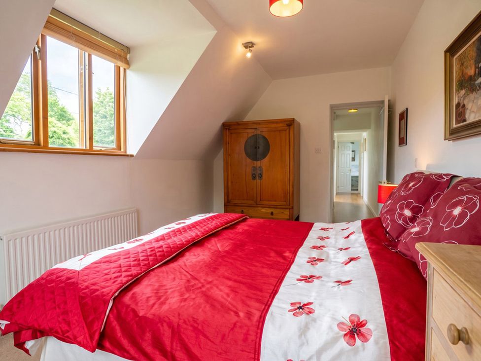 A bedroom with a red bed and wooden wardrobe at The Old Barn in Manchester