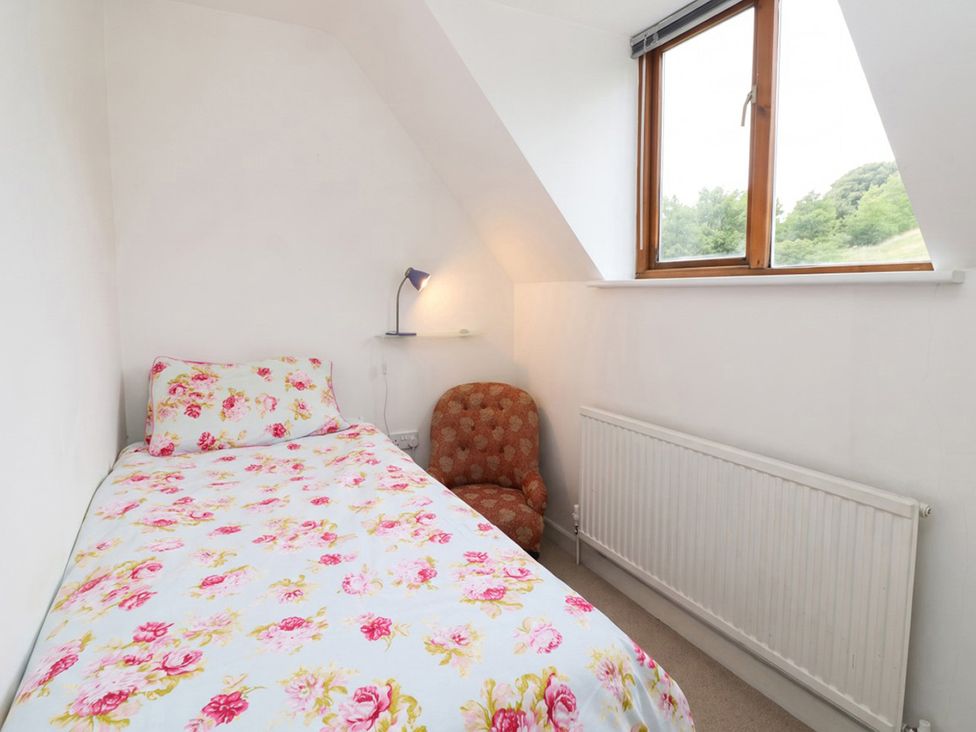 A bedroom with a bed, chair, lamp, radiator and window at 
