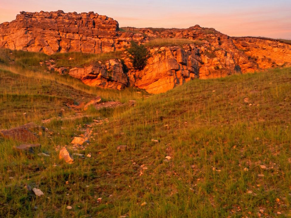 A landscape with rocks and grass at an outdoor location 