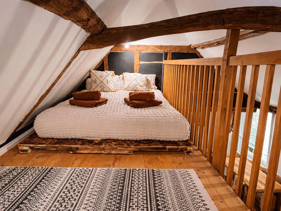 A loft bedroom with a bed and wooden beams in a property