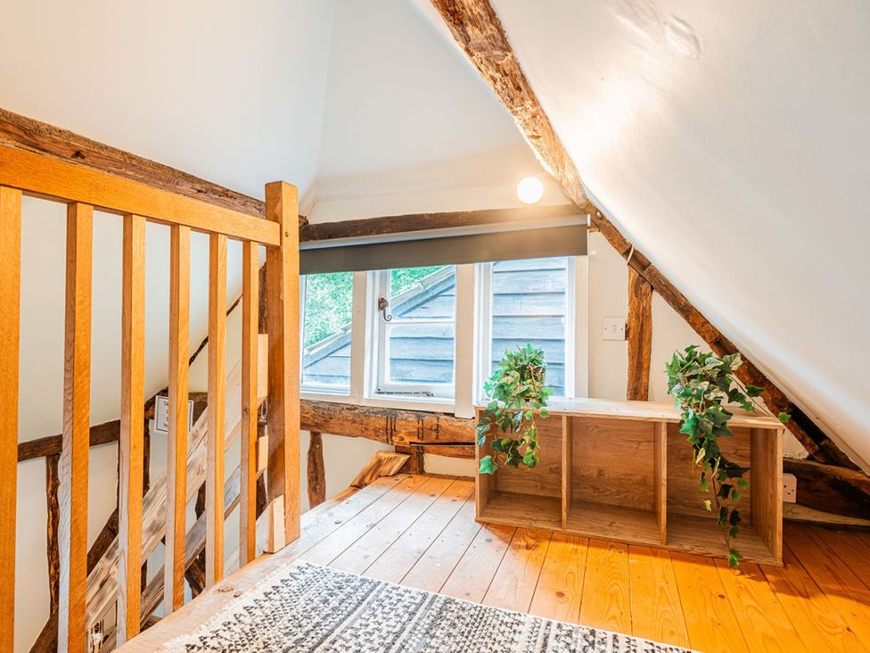 An attic space with wooden railing and a shelf with plants at the property in 