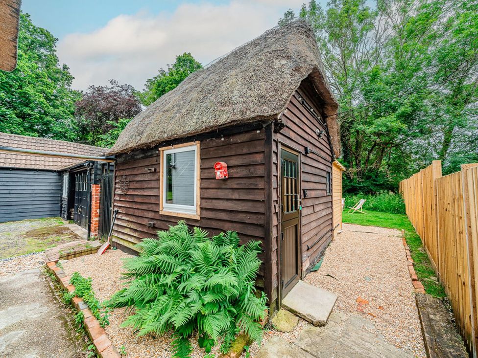 A wooden structure with a thatched roof and plants at a property