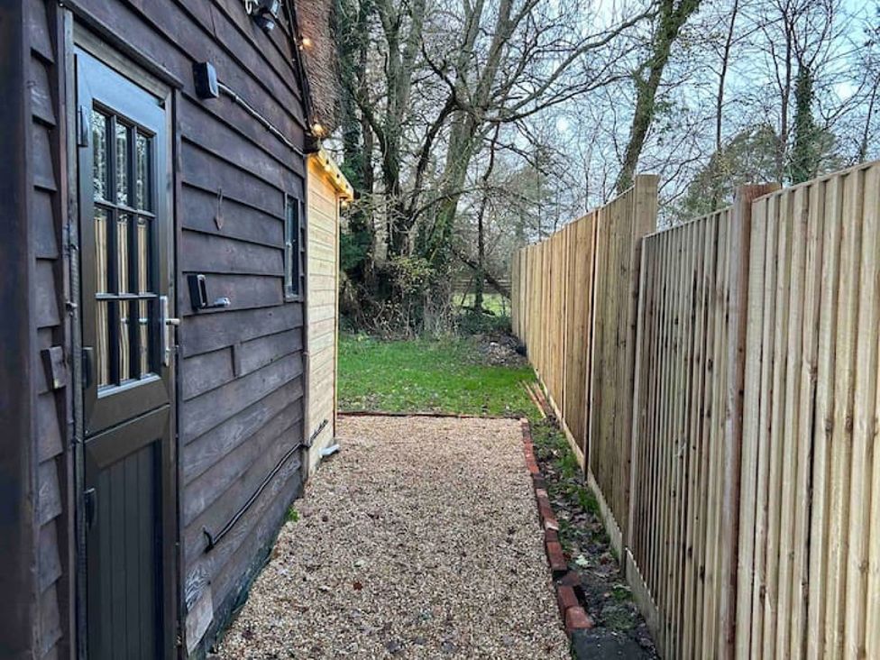 An outdoor pathway beside a house with a fence and trees at 