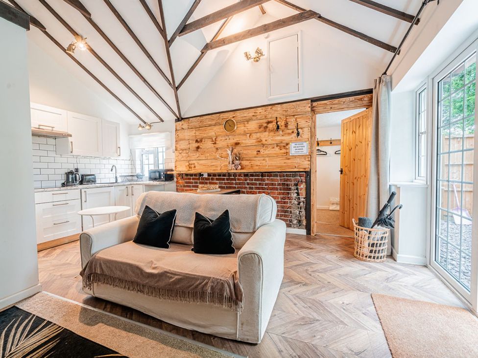 A living room with a sofa and kitchen area at a property