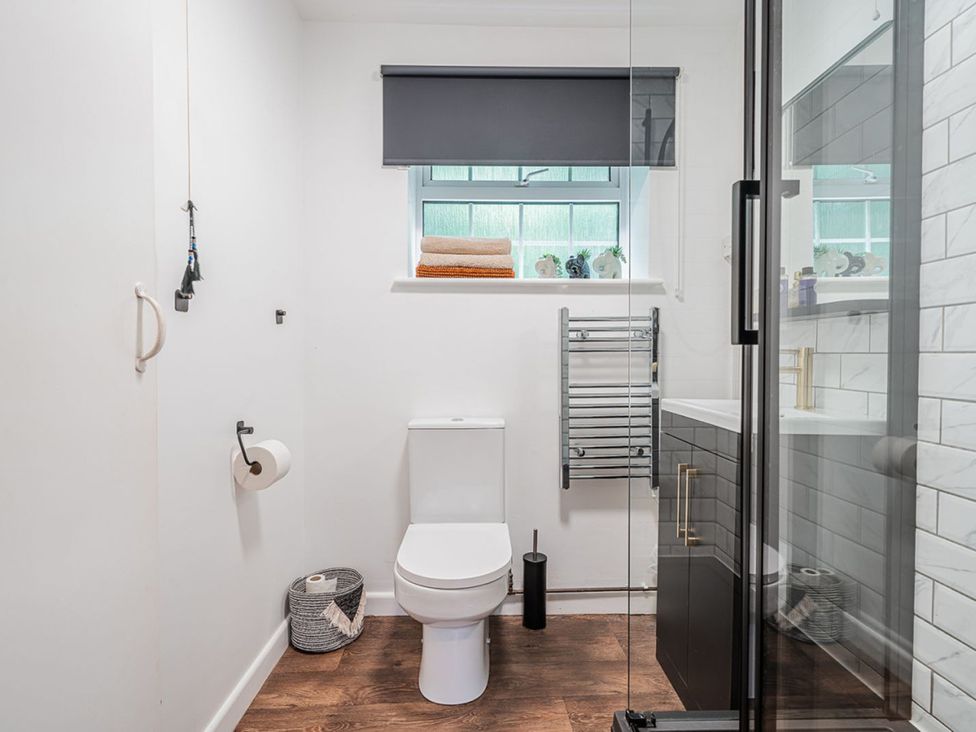 A bathroom with a toilet, shower, sink, and towel rack at The Old Barn in Manchester