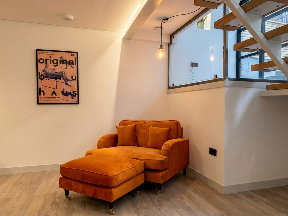 A sitting room with an orange chair and footrest at Emery Street Lodge