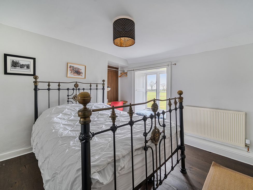 A bedroom with a bed and artworks on the wall at Furzen Farmhouse