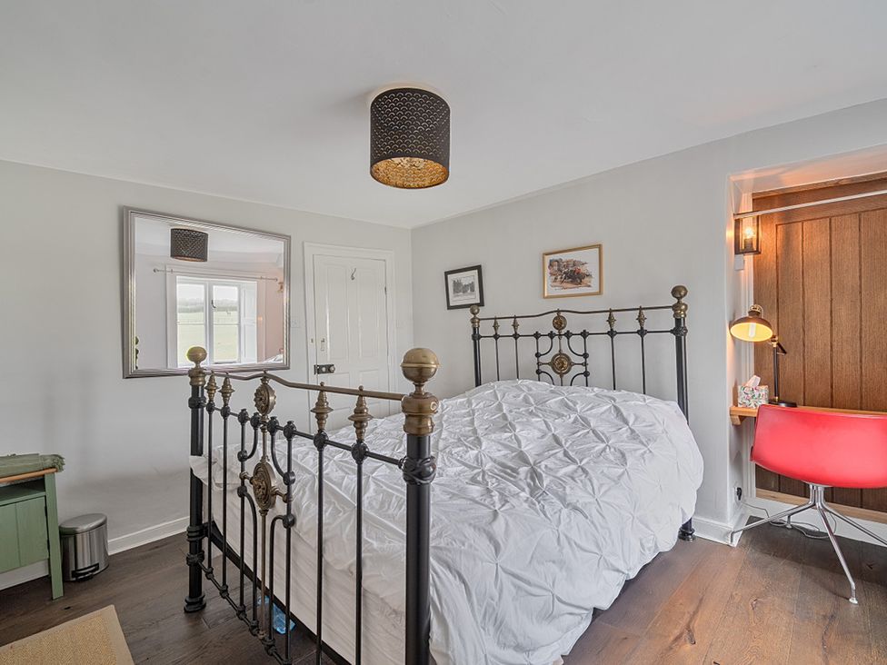 A bedroom with a bed and a desk at Furzen Farmhouse