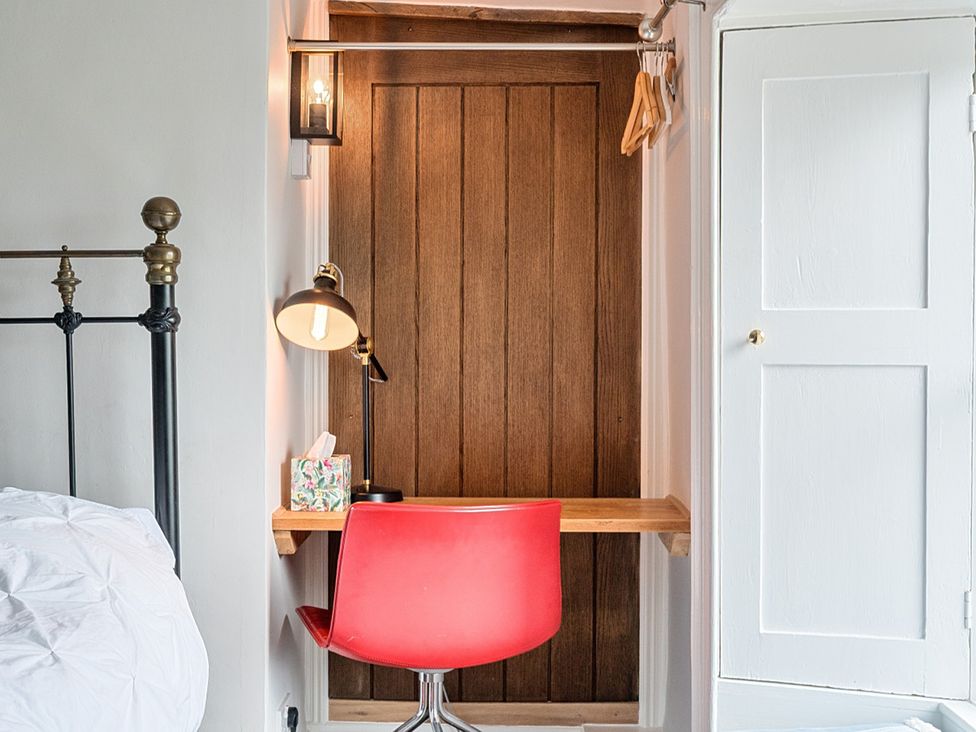 A bedroom with a red chair and a small table at Furzen Farmhouse
