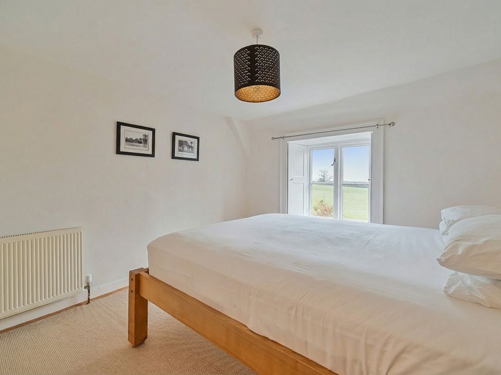 A bedroom with a bed and window at Furzen Farmhouse