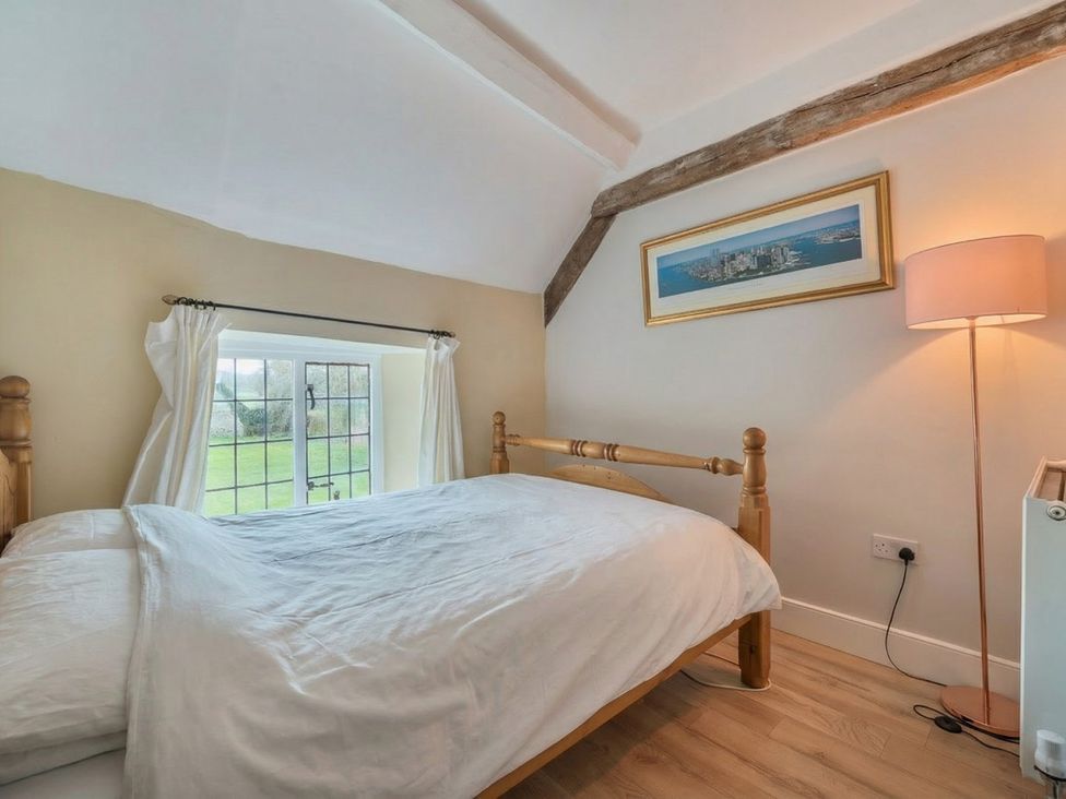 A bedroom with a bed and window at Furzen Farmhouse