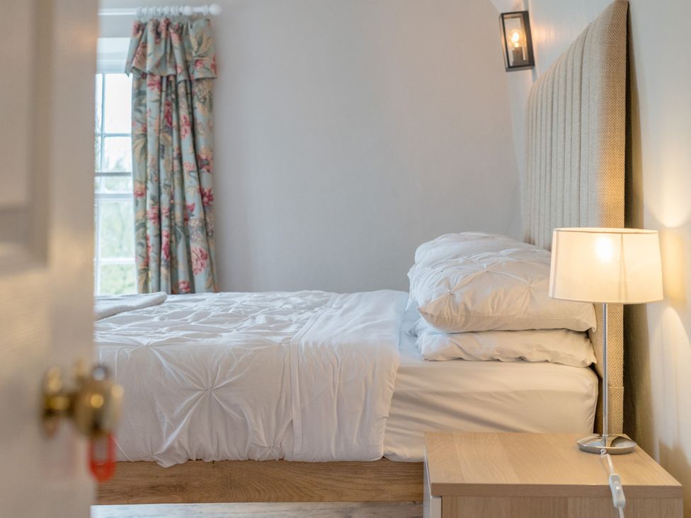 A bedroom with a bed and curtains at Furzen Farmhouse