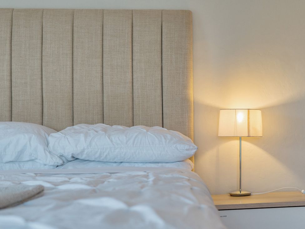 A bedroom with a bed and lamp at Furzen Farmhouse