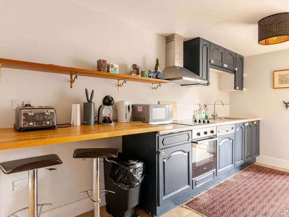 A kitchen with a stove, sink, and various appliances at Furzen Farmhouse