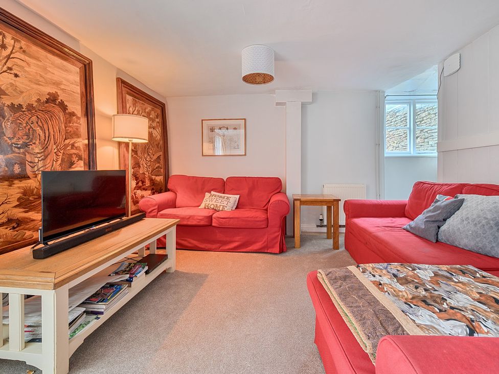A living room with a television and sofas at Furzen Farmhouse