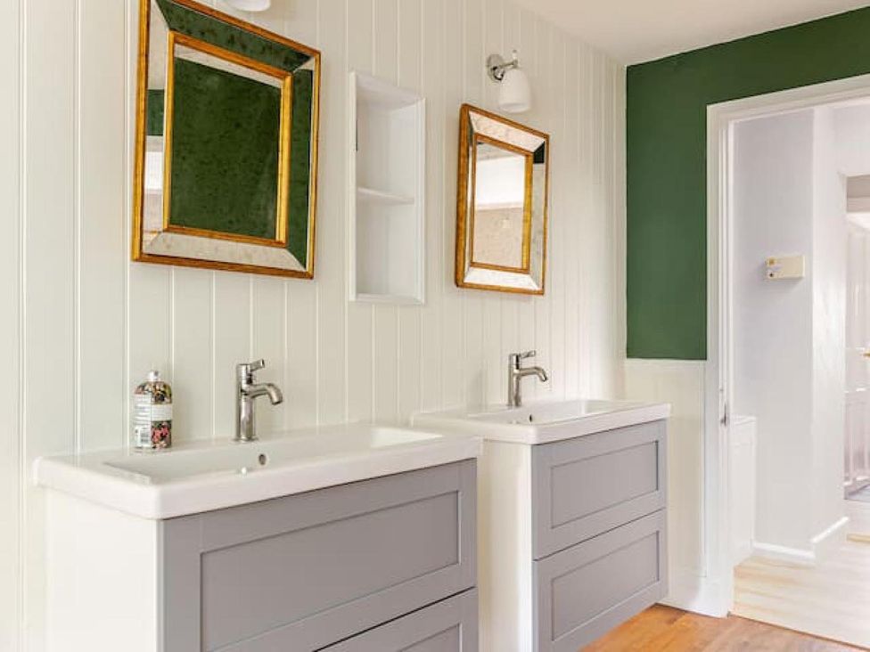 A bathroom with two sinks and mirrors at Furzen Farmhouse