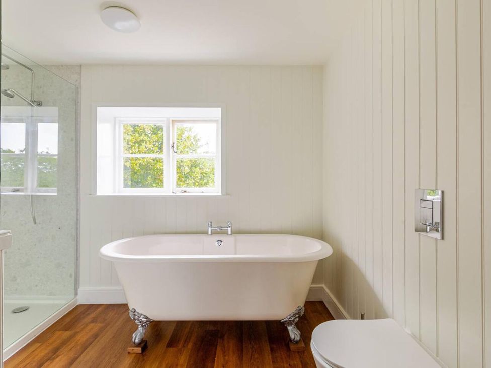 A bathroom with a bathtub and toilet at Furzen Farmhouse